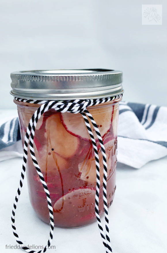 jar of pickled radishes with black and white string ties around them