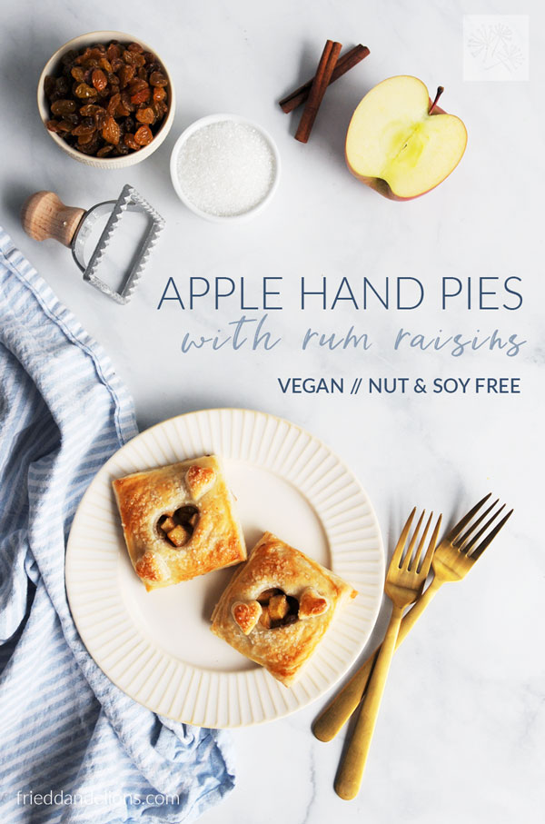 overhead view of apple hand pies with text overlay, apples and raisins in background, gold forks