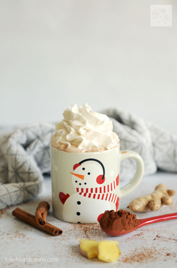 small mug with snowman image filled with vegan hot chocolate and topped with whipped cream