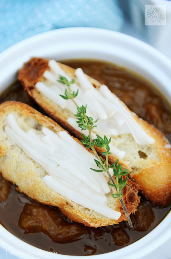 close up of bowl of French onion soup with sliced baguettes on top