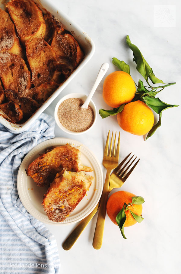 overhead view of vegan french toast casserole with oranges, gold forks, casserole dish in background