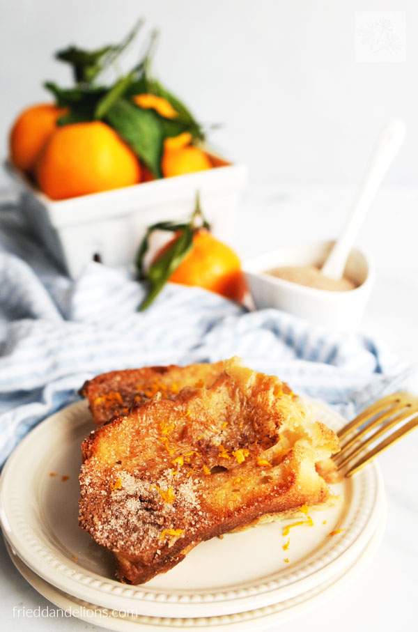 close up view of vegan french toast casserole on white plate with oranges in the background