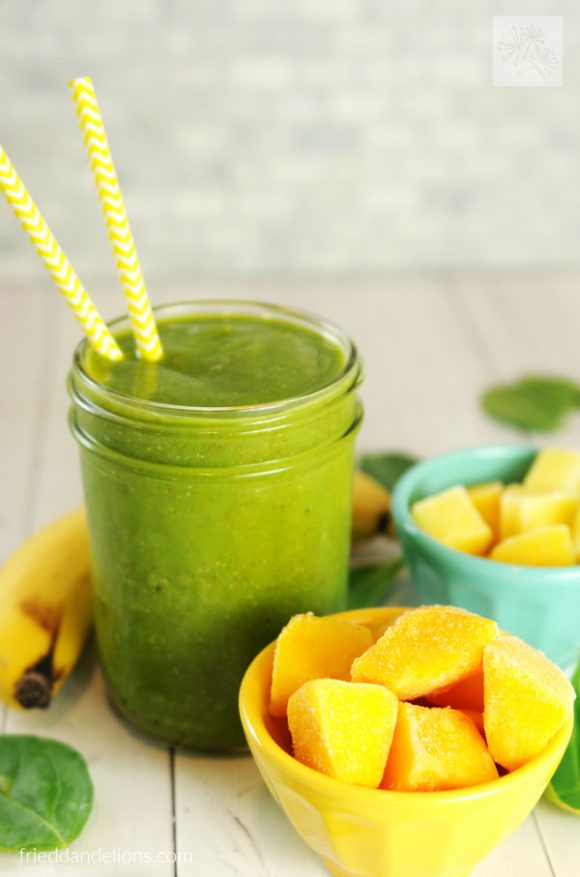 close up of citrus explosion green smoothie with bowl of mango in front