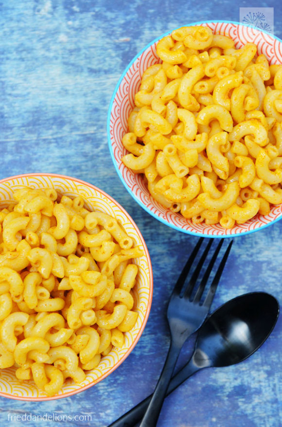 close up of two bowls of Vegan Boxed Mac and Cheese with blue background and black silverware