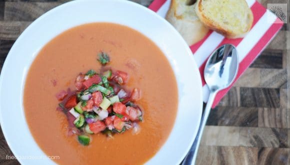 bowl of Watermelon Gazpacho with red and white striped napkin, spoon, and toasted bread in the background