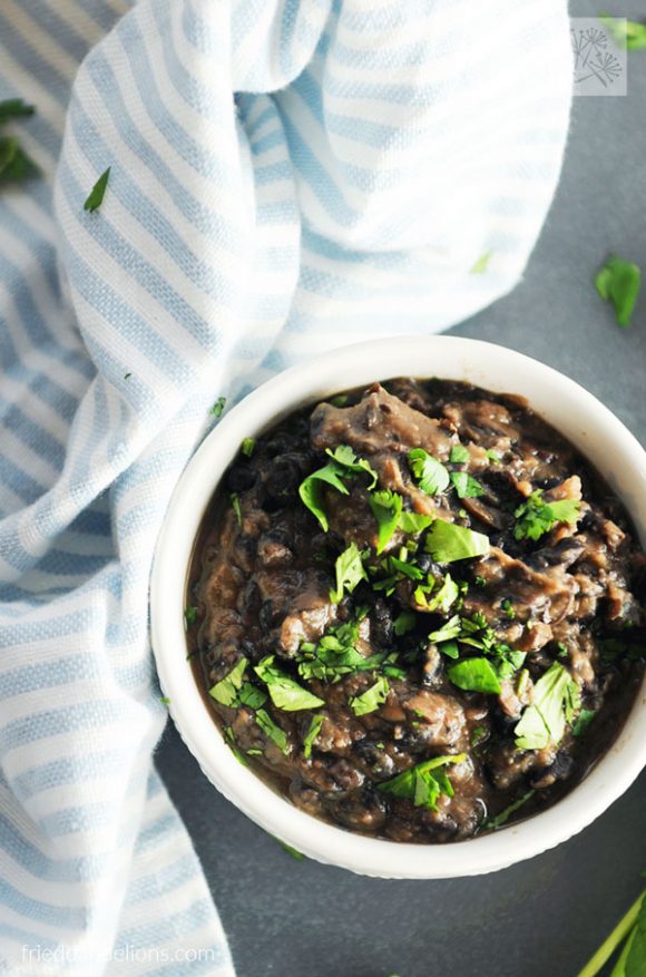 Easy vegan oil free refried black beans are a cinch to whip up a busy weeknight! Made only from pantry staples, you'll have them on the table in about 20 minutes! overhead view of vegan oil free refried black beans with blue and white striped napkin in the background