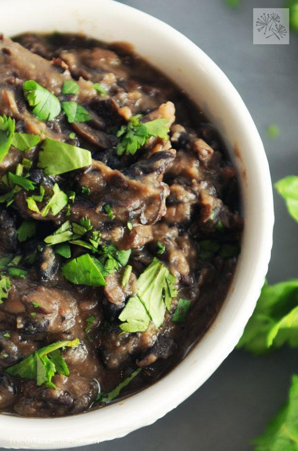 Easy vegan oil free refried black beans are a cinch to whip up a busy weeknight! Made only from pantry staples, you'll have them on the table in about 20 minutes! close up view of bowl of vegan oil free refried black beans