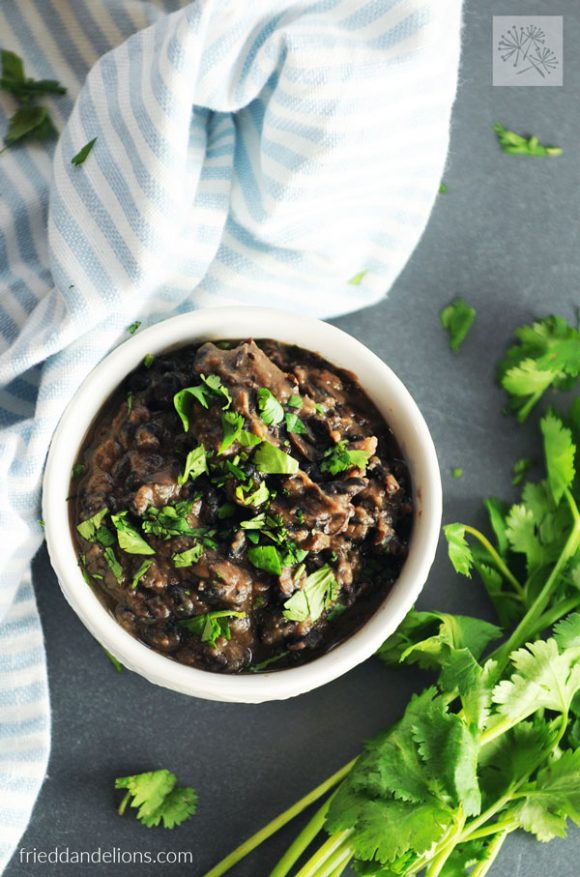 bowl of refried black beans with blue and white striped napkin and cilantro