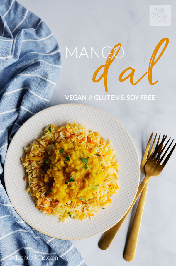 plate of mango dal and coconut carrot rice with text overlay, gold forks, blue napkin