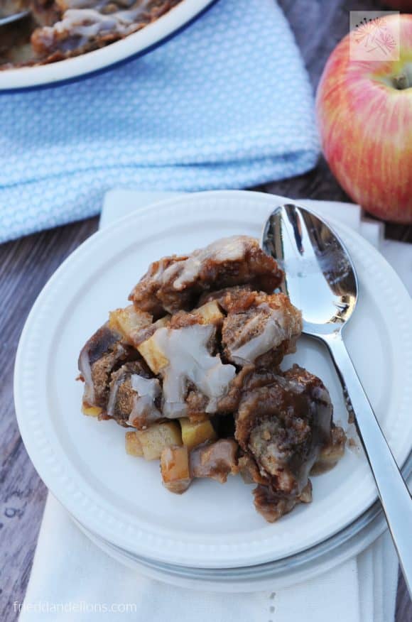 plate of Cinnamon Roll Bread Pudding with spoon and apple in background