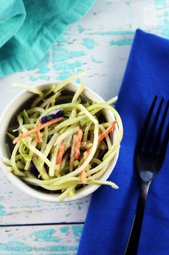 bowl of Broccoli Slaw with Oil Free Tahini Dressing with blue and aqua cloth napkins and black fork