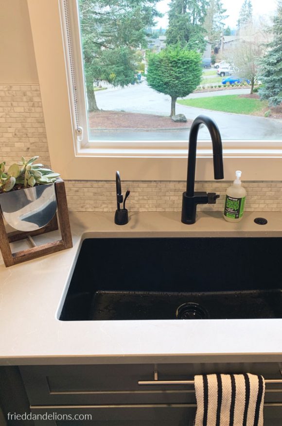 view of black quartz single basin sink with matte black faucet and instant hot water in grey kitchen renovation