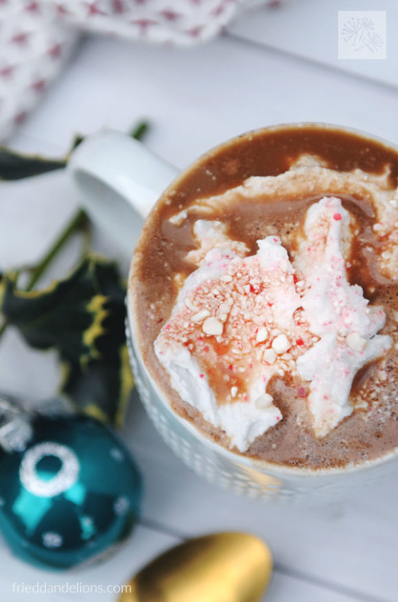 mug of coffee with dairy free peppermint mocha creamer topped with coconut whipped cream and crushed candy canes