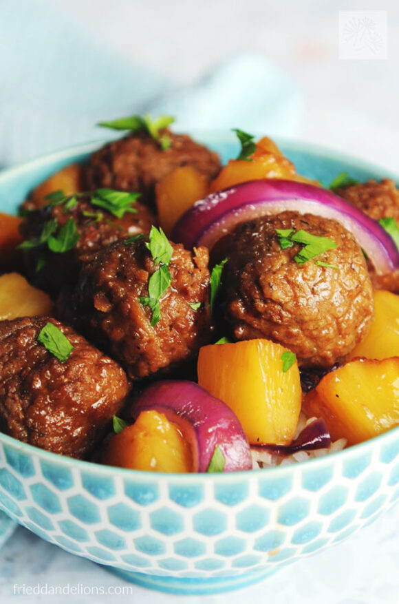 blue bowl filled with vegan Waikiki meatballs, yellow pineapple, red onion slices