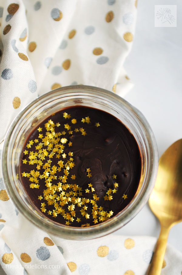 overhead view of vegan vanilla pudding cup with gold star sprinkles, gold spoon, and gold and silver napkin in background