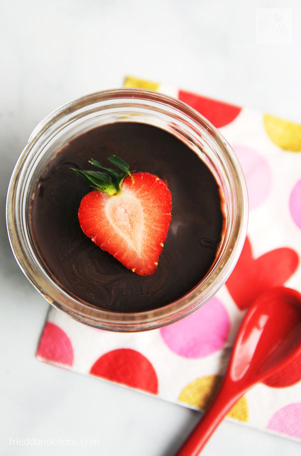 overhead view of vegan vanilla pudding cup with strawberry garnish, red spoon, and napkin with red heart