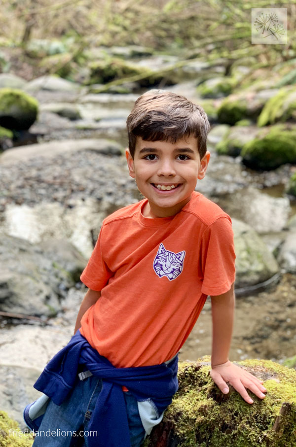 boy in orange shirt on the river bank