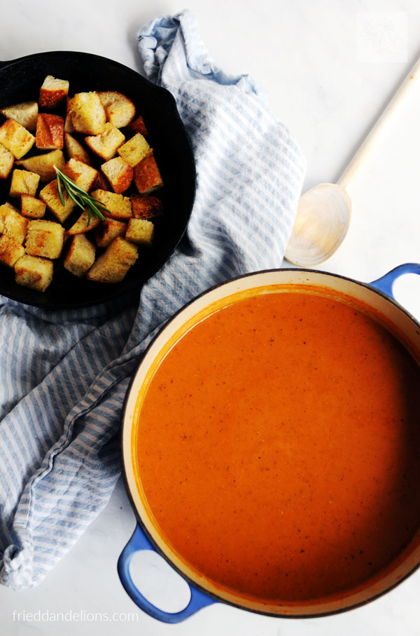 pot of vegan tomato soup with skillet full of homemade croutons, blue striped napkin in background