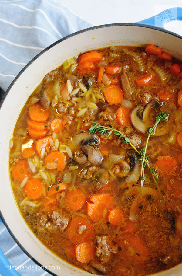 close up of large pot of Vegan Beef and Orzo Soup with sprigs of thyme